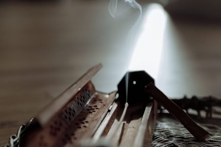 A wooden incense holder emitting smoke in a serene indoor setting, highlighting tranquility.